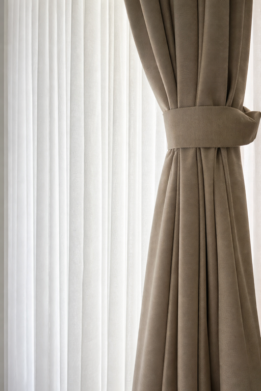 איסוף וילון בז' כבד בעזרת רצועת בד רחבה ותואמת ליצירת נפילה רכה של הבד.