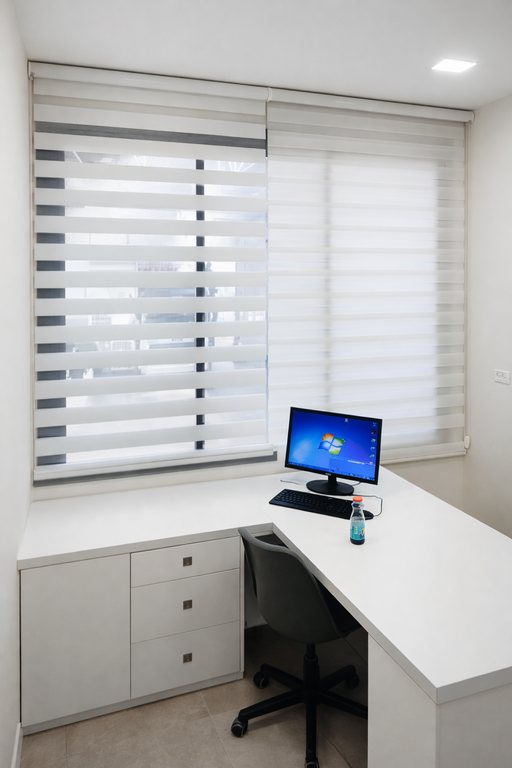 וילון זברה בשלושה חלקים על חלון משרד מול שולחן כתיבה מעץ ומסך מחשב.