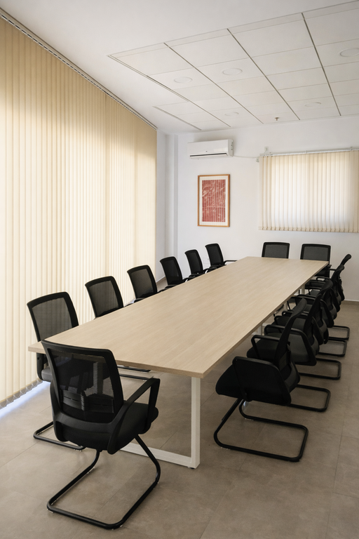 וילון ורטיקלי גבוה בצבע בז' בחדר ישיבות ארוך עם שולחן עץ רחב וכסאות משרד שחורים.