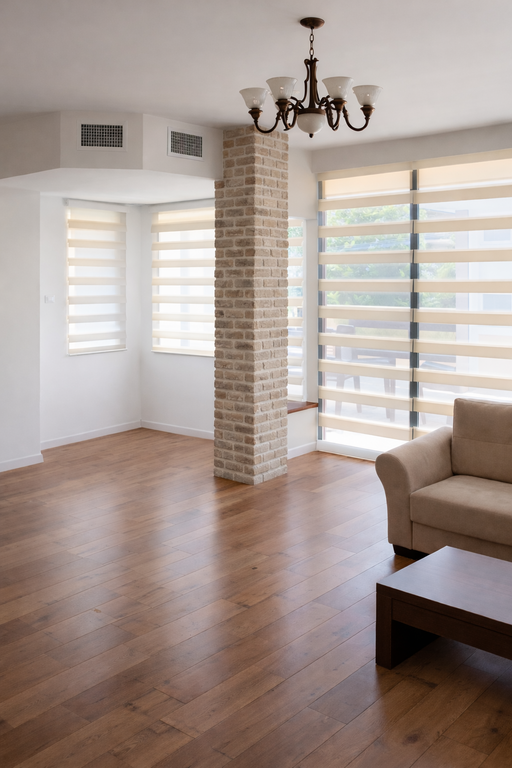 וילונות זברה (אור וצל) מותקנים בסלון עם עמוד בריקים, פרקט עץ וגוף תאורה קלאסי.