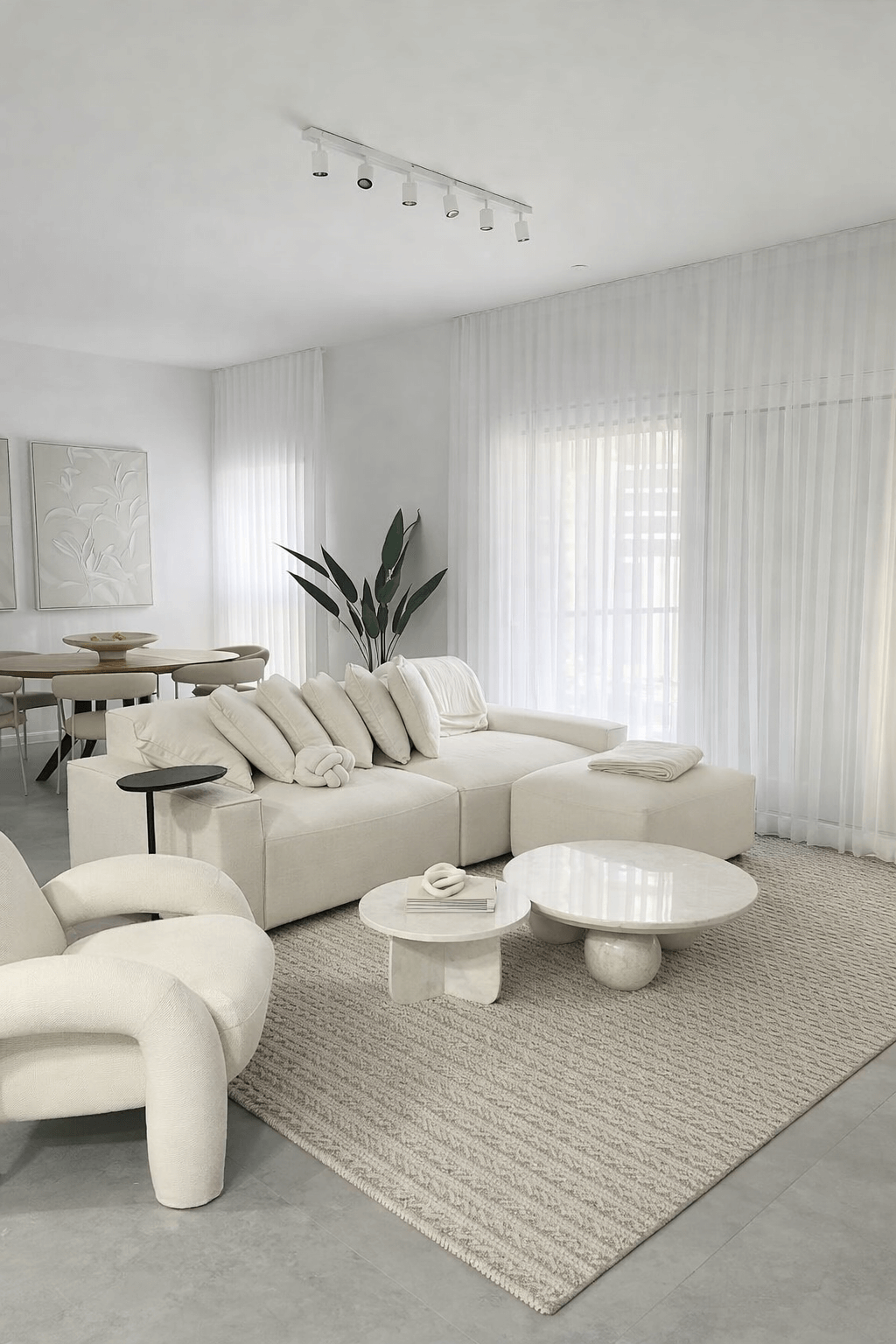 עיצוב סלון מינימליסטי הכולל ספה רחבה בגוון גרז', שולחן קפה מאבן טבעית ווילונות חצי שקופים.