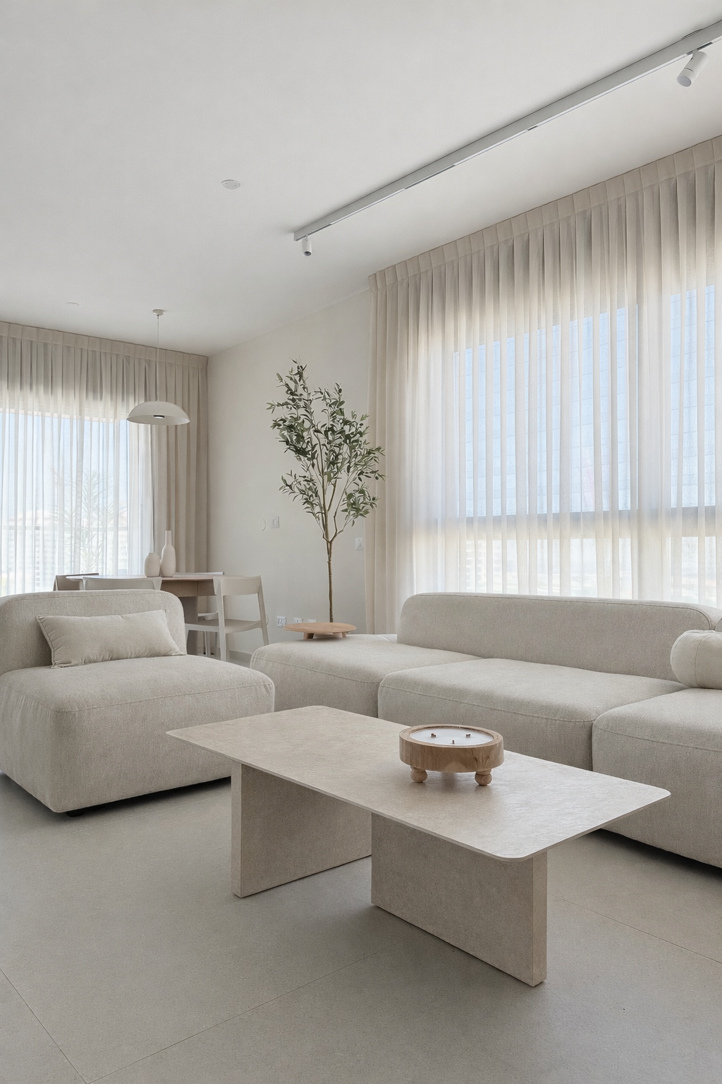 עיצוב סלון מודרני בגווני שמנת עם כורסת בוקלה עגולה, ספה מודולרית ושולחנות קפה משיש.