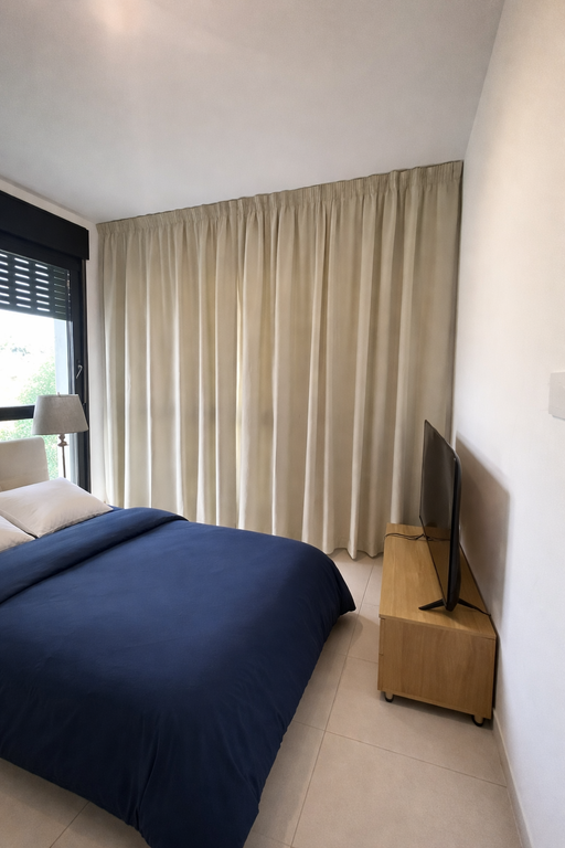 וילון רומי בגוון מוקה בחדר שינה עם ארון לבן ושני הדומים קטנים בצהוב וכחול.