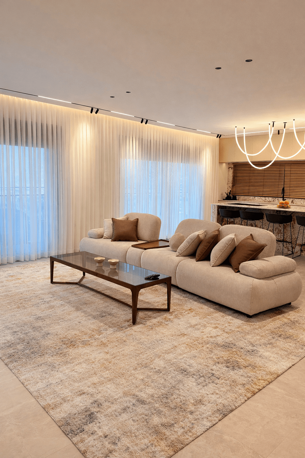 ספה רחבה ומפנקת עם כריות נוי בצבע חום שוקולד בסלון עם שטיח גדול ותאורת תקרה נסתרת.