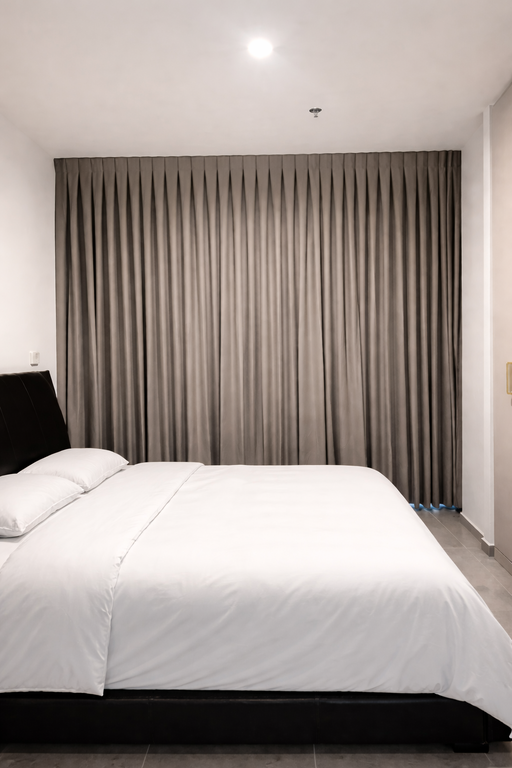 וילון רומי לבן חצי שקוף מעל ספסל ישיבה מרופד בפינה מוארת בבית.