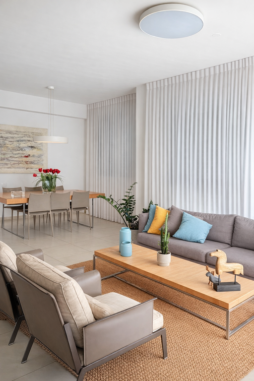 וילונות לבנים מעוצבים לסלון רחב, המשתלבים עם ריהוט מודרני, שטיח חבל ופינת אוכל ברקע.