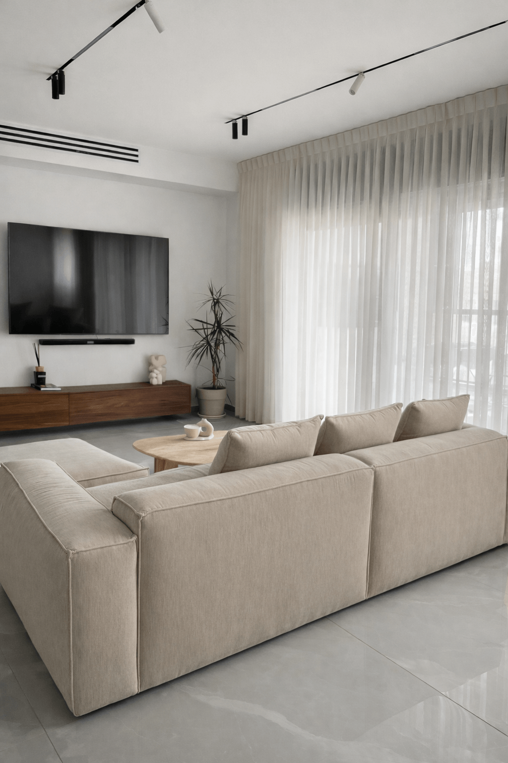עיצוב סלון מודרני עם ספה מודולרית בגוון בז', עציץ זית דקורטיבי ווילונות בהירים נשפכים.